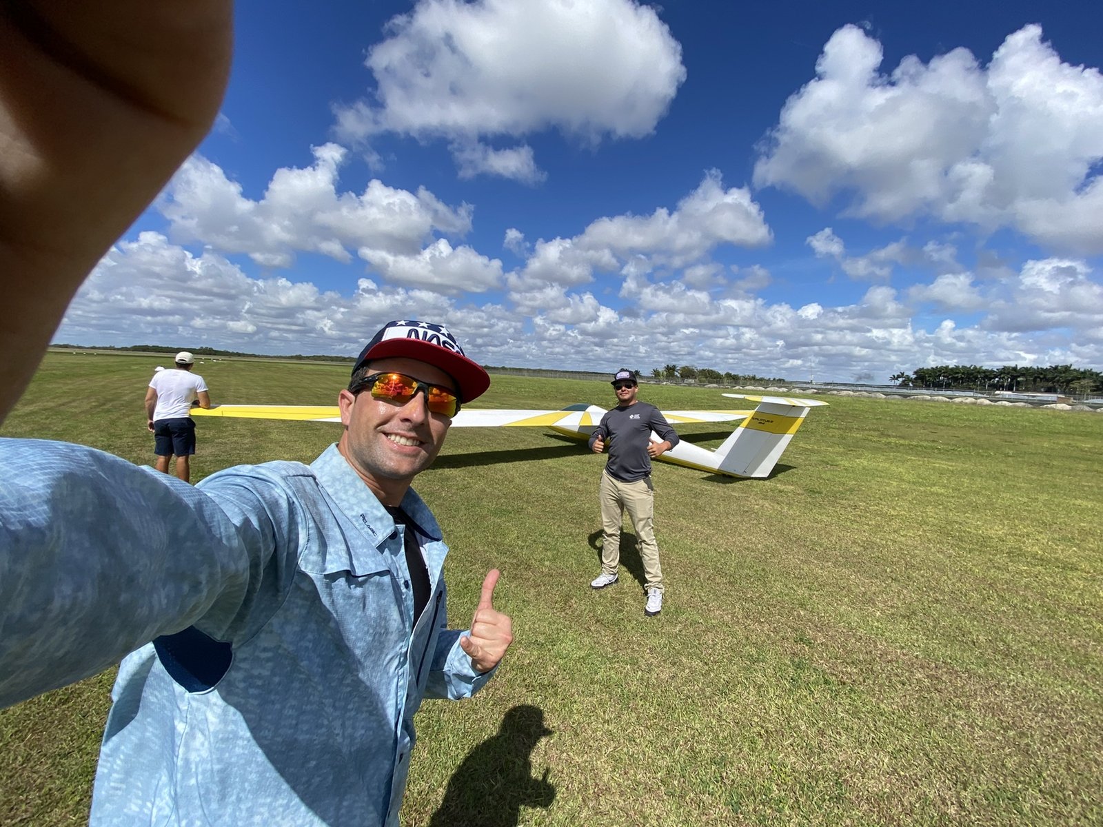 Crew at the gliderport with a sailplane on the grass behind them