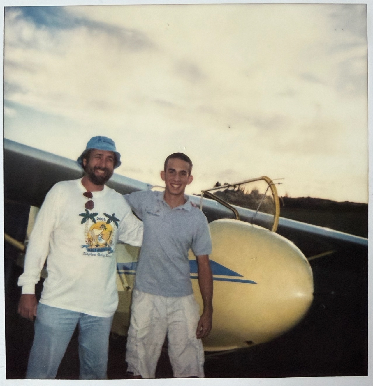 Polaroid of Angel Delguy as a teenager standing beside a sailplane with instructor Barry Barkman after his first solo at Homestead General Airport, circa 2003-2004