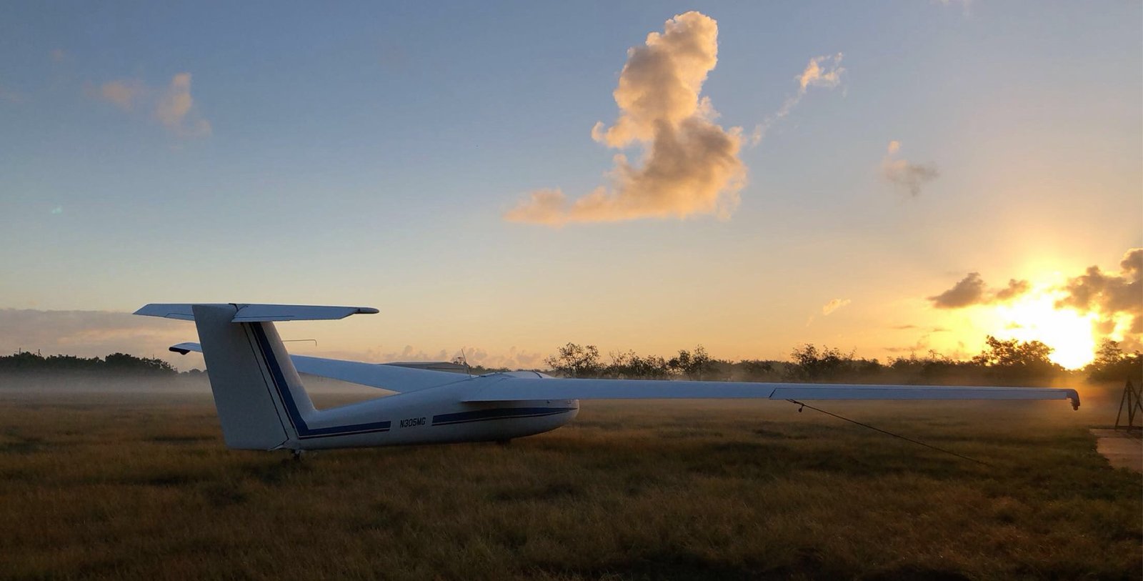Blanik L-23 tied down at sunrise with mist drifting across the field